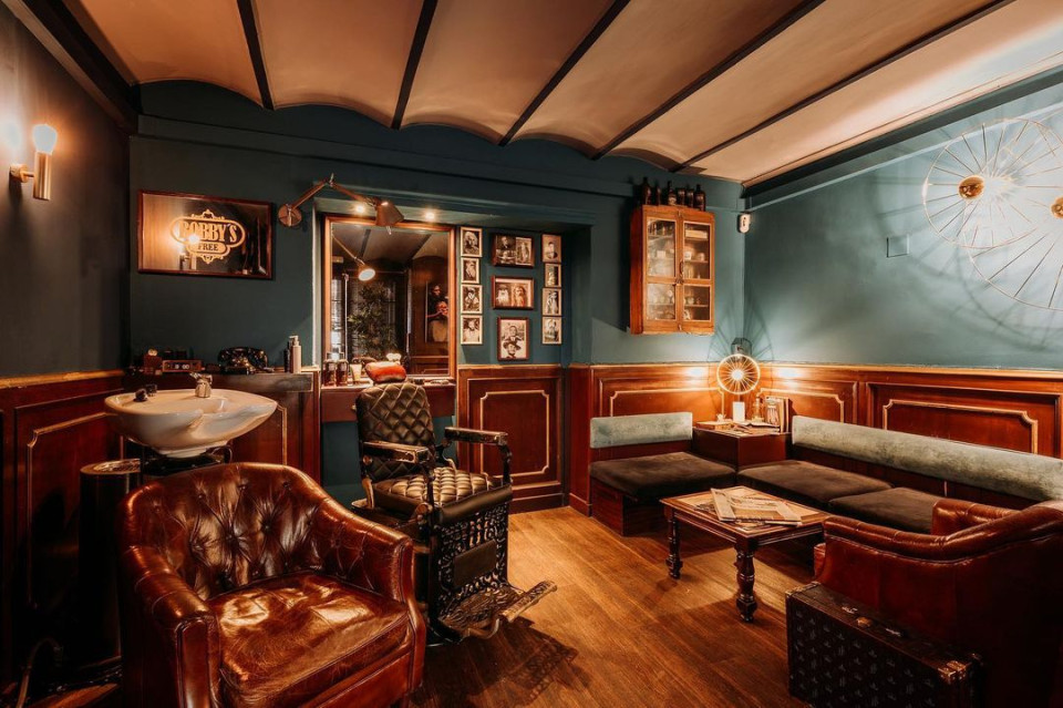 Vintage style barbershop with leather seats and wood panelling.