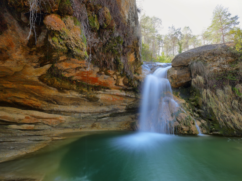 small waterfall going over layered rock face.