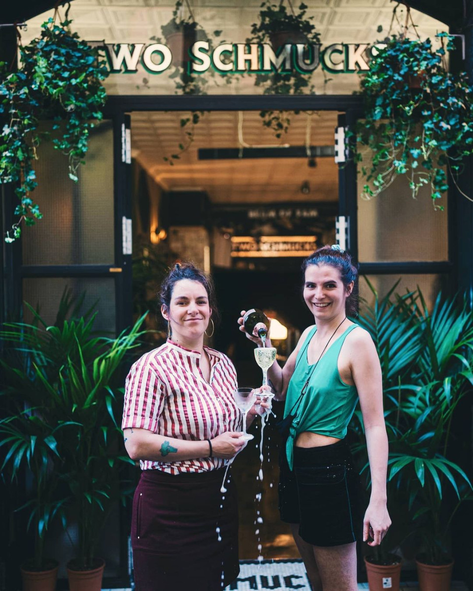 Two women posing with cava outside of cocktail bar.